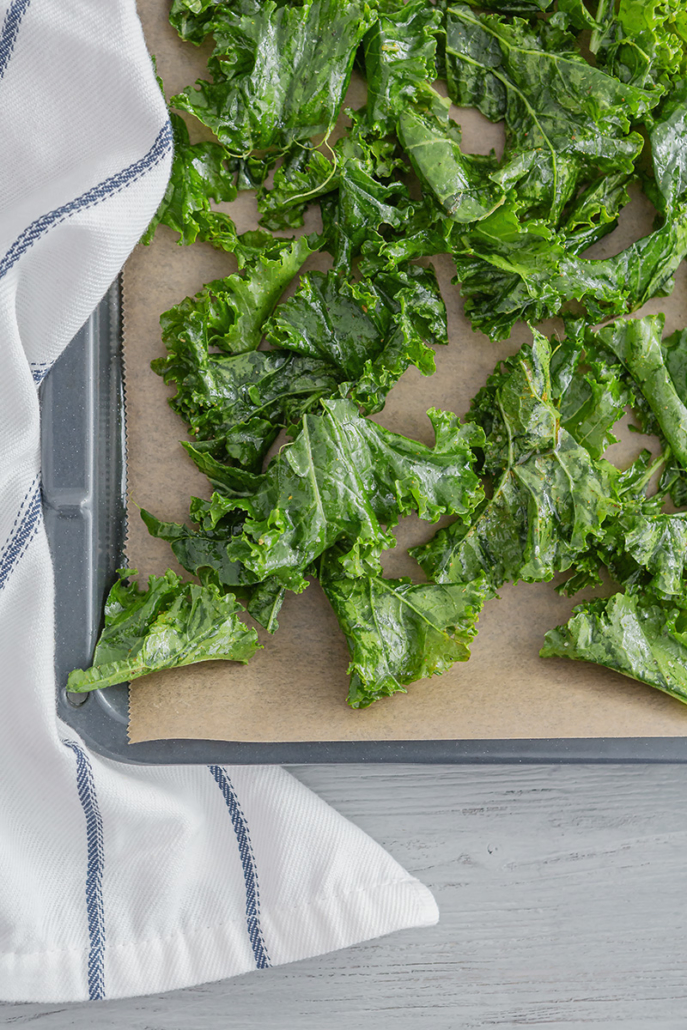 Marinierter Grünkohl verteilt auf einem mit Backpapier ausgelegten Backblech