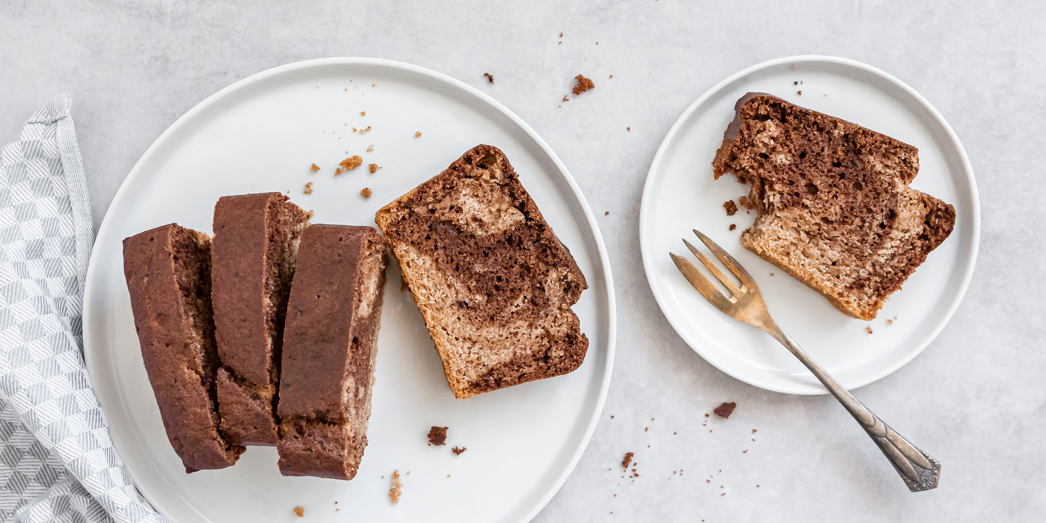Grosser Teller mit vier Stück Marmorkuchen. Daneben steht ein kleinerer Teller mit einem angebissenem Stück Marmorkuchen und einer Kuchengabel.