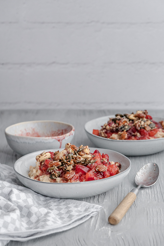 Warmes Frühstück aus Porridge, Pflaumenkompott und Nüssen mit einem Hauch Zimt.