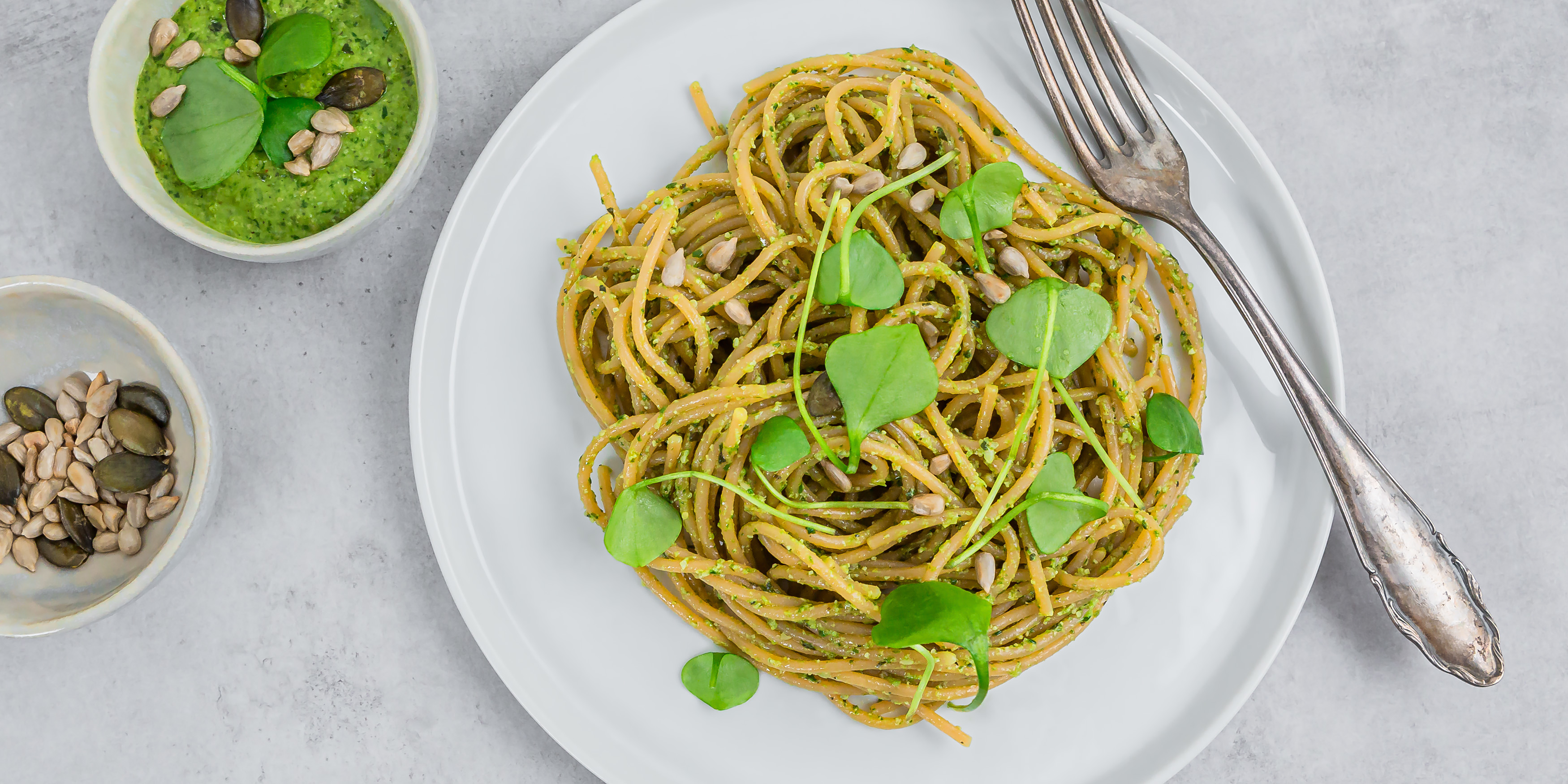 Teller mit Spaghetti aus roten Linsen mit einem Pesto aus Portulak steht zum Essen bereit.