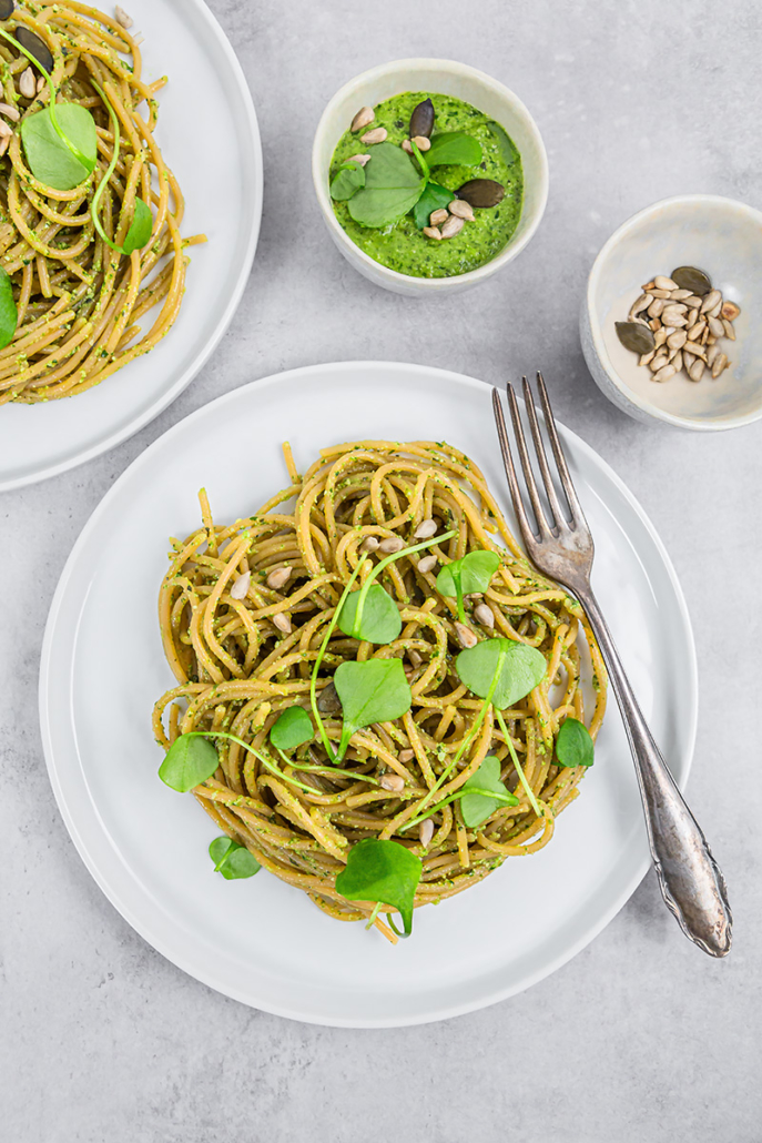 Teller mit Spaghetti aus roten Linsen mit einem Pesto aus Portulak steht zum Essen bereit.