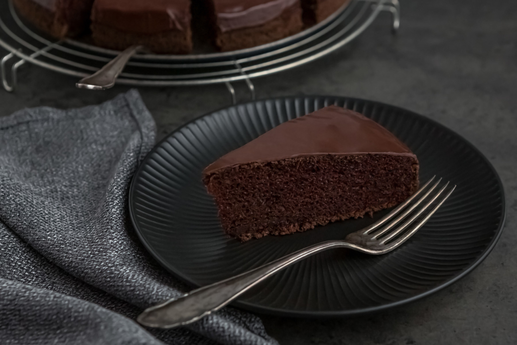 Teller mit einem Stück veganem Sckokokuchen und einer Gabel