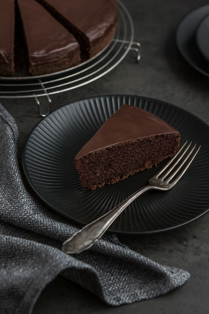Teller mit einem Stück veganem Sckokokuchen und einer Gabel