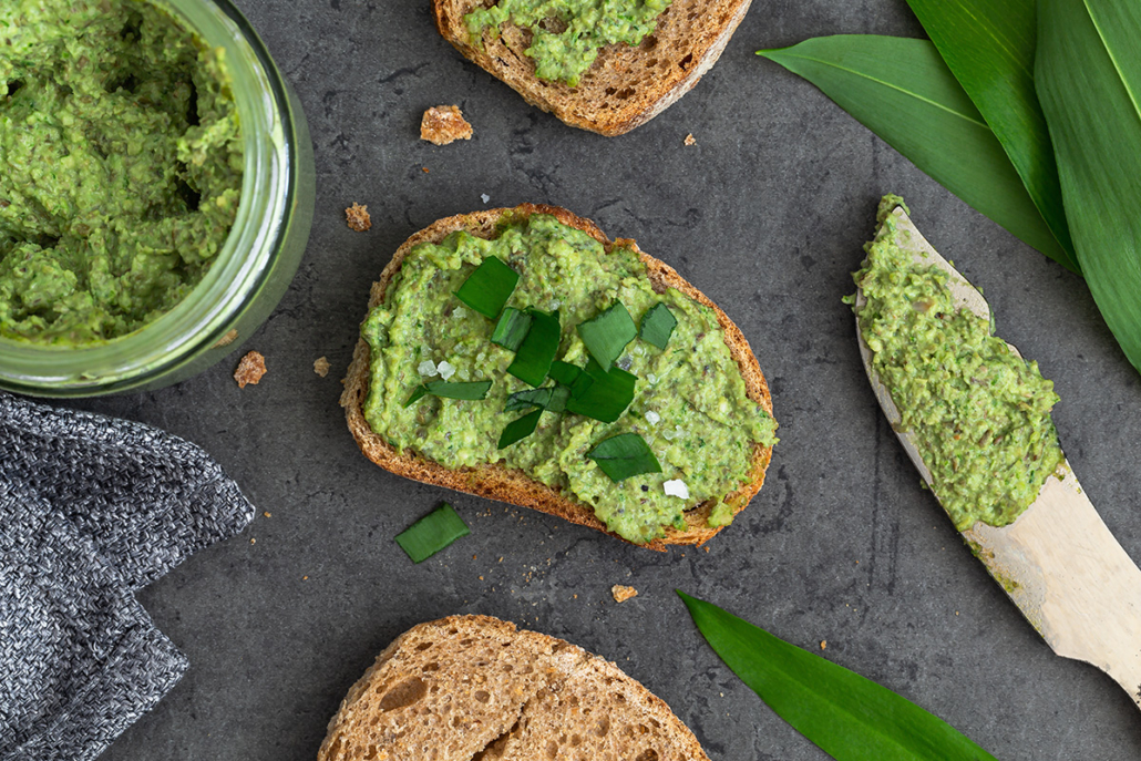 Brot bestrichen mit Bärlauch-Linsen-Aufstrich, daneben steht das Glas mit dem Aufstrich.