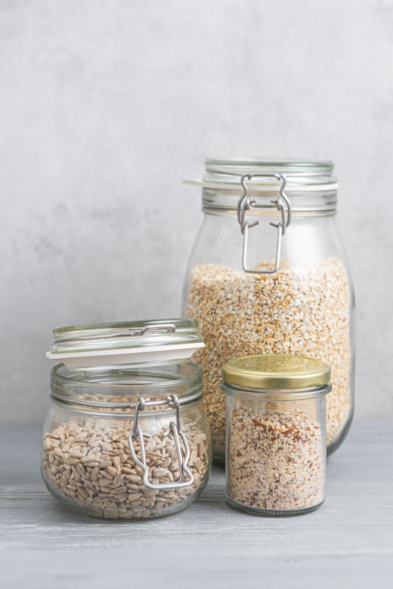 Vorratsgläser mit Mandeln, Haferflocken und Sonnenblumenkernen
